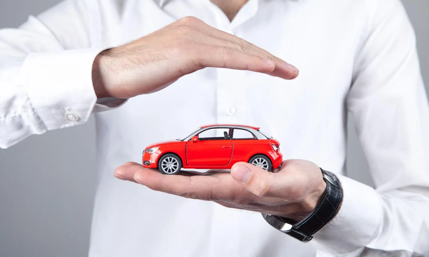 Open hand held over a small car as a sign of cover