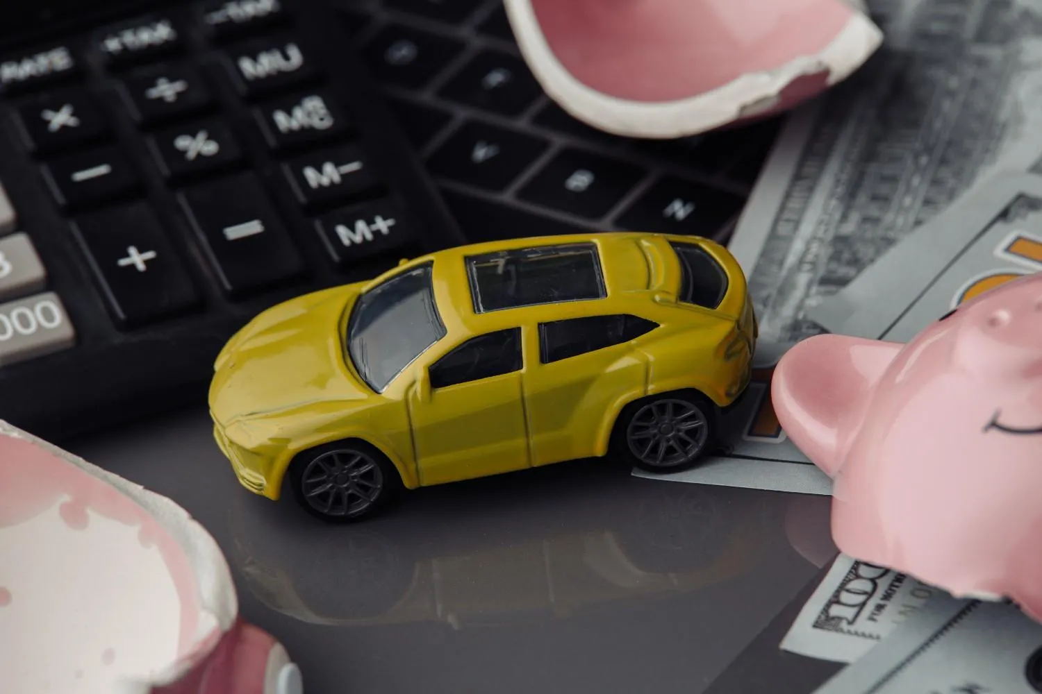 Small car sitting on a calculator beside saved notes